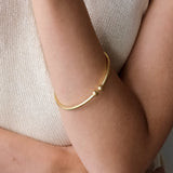 Gold bracelet on a person's wrist with a neutral background