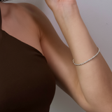 Silver rope bracelet on a person's wrist against a neutral background